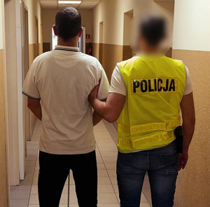 Policjant trzyma zatrzymanego mężczyznę.