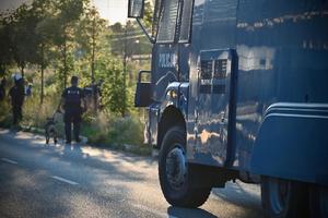 Armatka wodna na tle policjantów zabezpieczających mecz piłki nożnej.