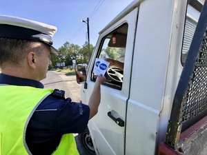Policjant wręcza materiały partnera akcji &quot;Zwolnij, mistrzu&quot;.