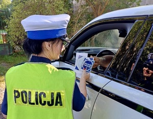 Policjantka wręcza materiały partnera akcji &quot;Zwolnij, mistrzu&quot;.