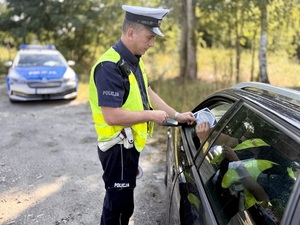 Policjant wręcza materiały partnera akcji &quot;Zwolnij, mistrzu&quot;.