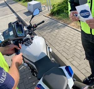 Policjant pokazuje wynik pomiaru prędkości motocykliście.