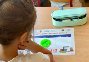 Na biurku uczennicy plan zajęć i odblask z logo akcji &quot;Bezpieczna droga do szkoły&quot; i WORD.