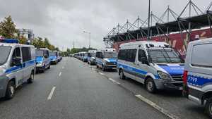 Policyjne radiowozy zaparkowane przed stadionem.