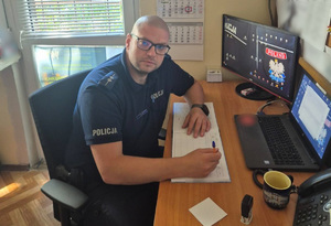 Aspirant Marcin Grzech siedzi przy biurku.