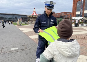 Policjantka wręcza odblaski dziecku.