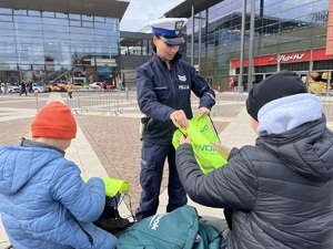 Policjantka wręcza odblaski dziecku.