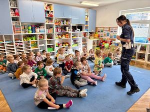 Policjantka rozmawia z przedszkolakami o bezpieczeństwie w ruchu drogowym.