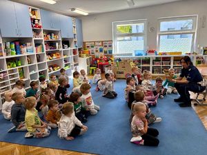 Policjantka czyta przedszkolakom książeczkę o bezpieczeństwie.