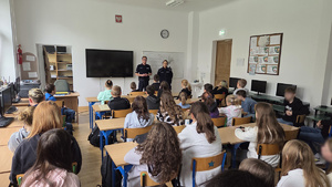 Umundurowani policjanci, w klasie, podczas zajęć z dziećmi.