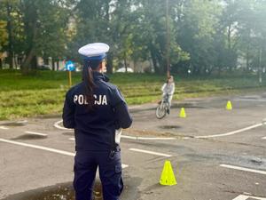 Policjantka ocenia praktyczne umiejętności jadącego rowerzysty.