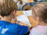 Dzieci rozwiązują test wiedzy pod nadzorem łódzkich policjantów.