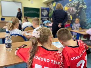 Dzieci rozwiązują test wiedzy pod nadzorem łódzkich policjantów.