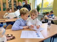 Dzieci rozwiązują test wiedzy pod nadzorem łódzkich policjantów.