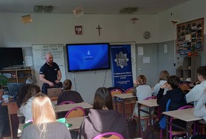 Umundurowany policjant, w klasie, w trakcie rozmowy z młodzieżą.