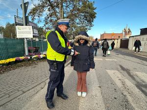 Policjant przekazujący odblask dziewczynce.