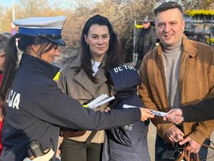 Policjantka rozdaje elementy odblaskowe.