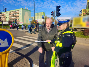 Policjantka zakłada element odblaskowy mężczyźnie.