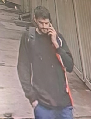 Mężczyzna o smukłej budowie ciała, włosy ciemne krótko ostrzyżone, wąsy oraz zarost.
Ubrany był w czarną kurtkę z czerwono białymi dodatkami po bokach, niebieskie jeansowe spodnie. Na plecach założony czarny plecak.