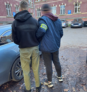 Zatrzymany prowadzony przez policjanta.