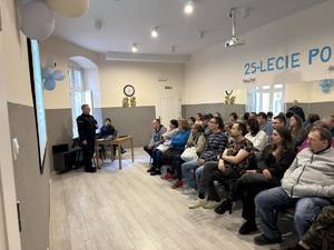 Policjanci prowadzą prelekcje. W tle uczestnicy spotkania.