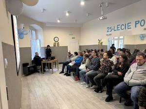 Policjanci prowadzą prelekcje. W tle uczestnicy spotkania.