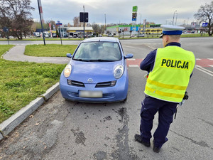 Policjant kontroluje stan oświetlenia pojazdu.