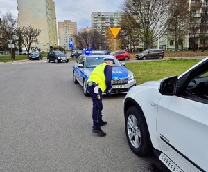 Policjant kontroluje stan oświetlenia pojazdu.