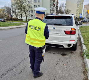 Policjant kontroluje stan oświetlenia pojazdu.