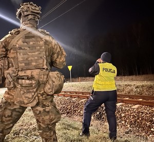 Policjantka i żołnierz w trakcie kontroli torowiska kolejowego.