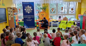 Policjant rozmawia z przedszkolakami o sygnalizacji świetlnej.