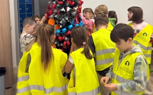 Dzieci dekorują choinkę.