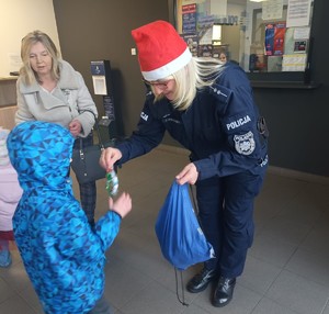 Policjantka rozdaje dzieciom drobne upominki.
