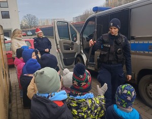 Policjantka prezentuje dzieciom sprzęt policyjny i radiowóz.