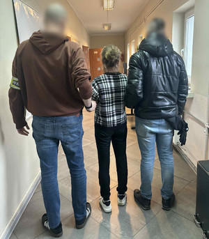 Policjanci stoją z zatrzymaną kobietą.