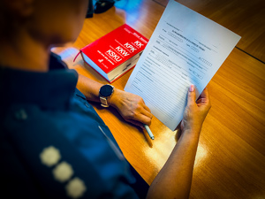 Policjant trzyma w ręce protokół zawiadomienia o przestępstwie.