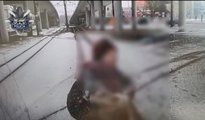 Kobieta stoi na torowisku przed tramwajem.