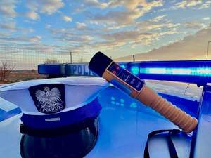 Czapka policyjna i alkomat leżą na dachu oznakowanego radiowozu.