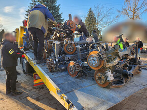 Policjanci zabezpieczają części samochodowe na lawecie.