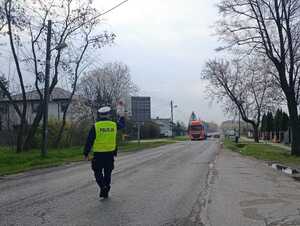 Policjant z Wydziału Ruchu Drogowego Komendy Miejskiej Policji w Łodzi zatrzymuje pojazd ciężarowy do kontroli drogowej.