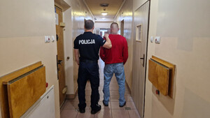 Policjant trzyma mężczyznę.