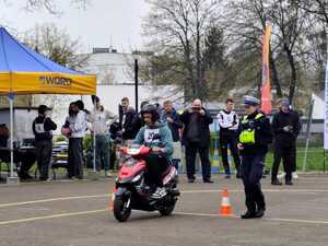Policjantka nadzoruje przejazd uczestnika eliminacji na skuterze.