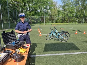 Zdjęcie poglądowe - policjantka z Wydziału Ruchu Drogowego Komendy Miejskiej Policji w Łodzi stoi na boisku, w tle stoją rowery.