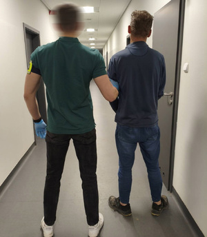 Policjant prowadzi podejrzanego.