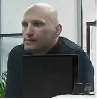 Mężczyzna bez zarostu na twarzy,  w wieku około 35-40 lat. Ubrany w sportową bluzę koloru czarnego .
