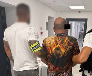 Policjanci prowadzą zatrzymanego mężczyznę.