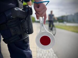 Policjant trzyma tarczę służącą do zatrzymywania pojazdów.