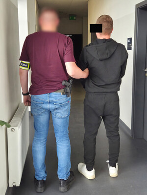 Policjant stoi z zatrzymanym mężczyzną.