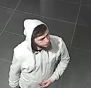 Mężczyzna w wieku około 25-35 lat z widocznym na twarzy zarostem koloru ciemnego, z włosami koloru ciemnego ubrany w bluzę z kapturem koloru szarego, spodnie koloru czarnego i buty sportowe koloru białego, w momencie kradzieży mężczyzna miał na głowę naciągnięty kaptur.