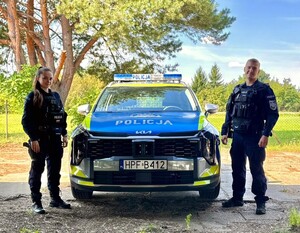 Umundurowani policjanci stoją przy radiowozie.